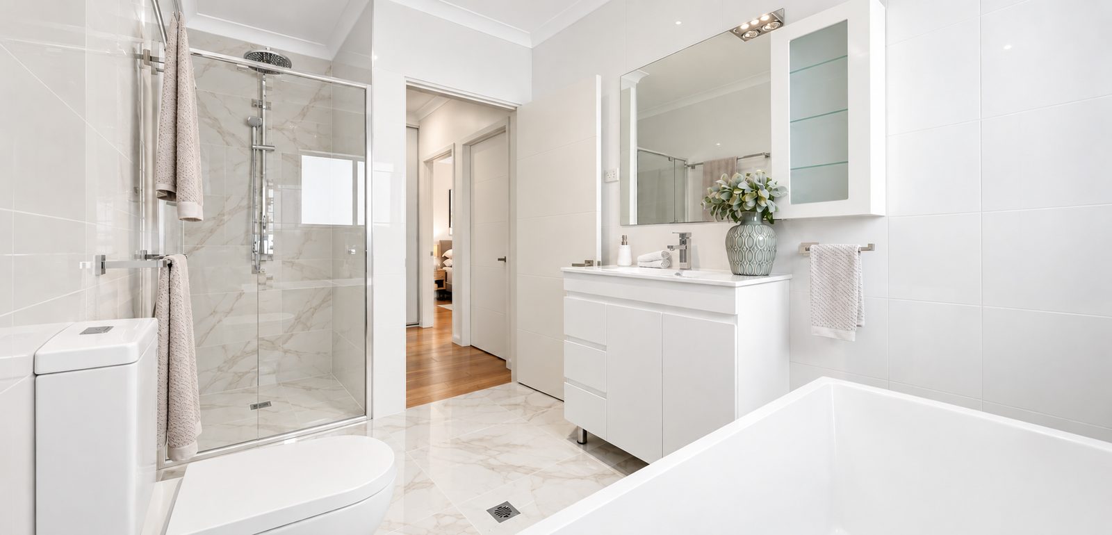 Moorebank bathroom with a glass shower screen, freestanding bath and white vanity