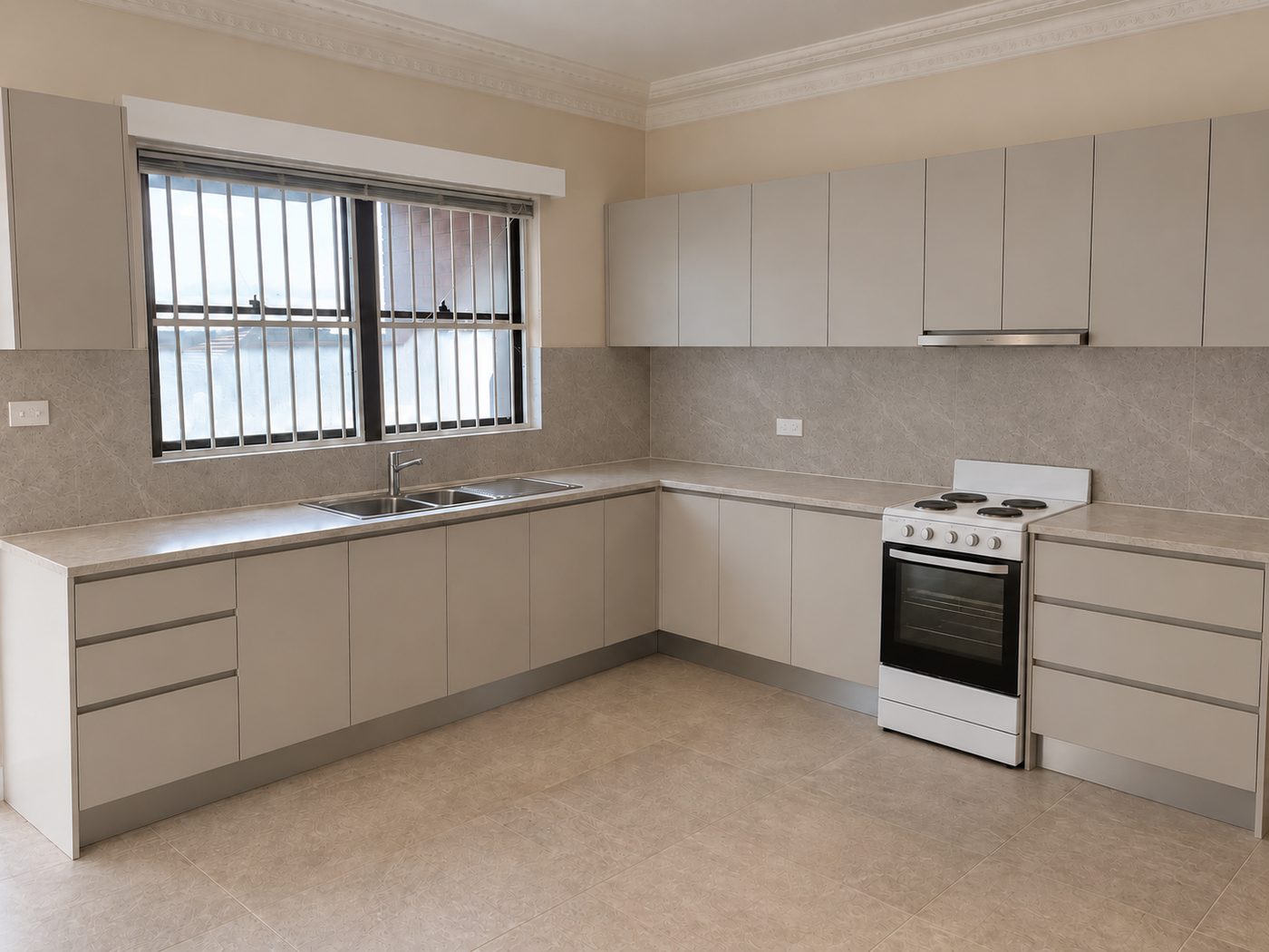 Padstow kitchen after renovation, with soft grey handleless cabinets, stone-look splashback and new tiled floor
